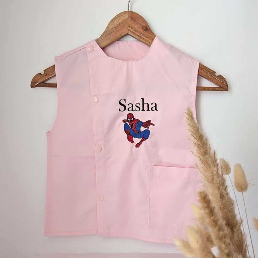 Tablier en tissus pour école maternelle couleur rose modèle sans manches pour garçon brodé du prénom en bleu