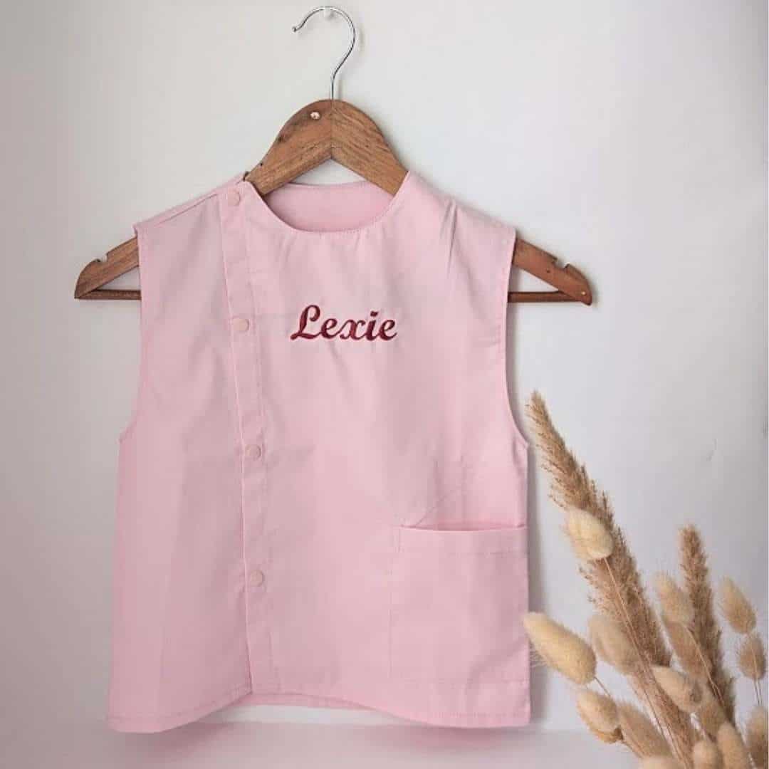 tablier ecole rose(10) Tablier en tissus pour école maternelle couleur rose modèle sans manches pour filles brodé du prénom en rouge