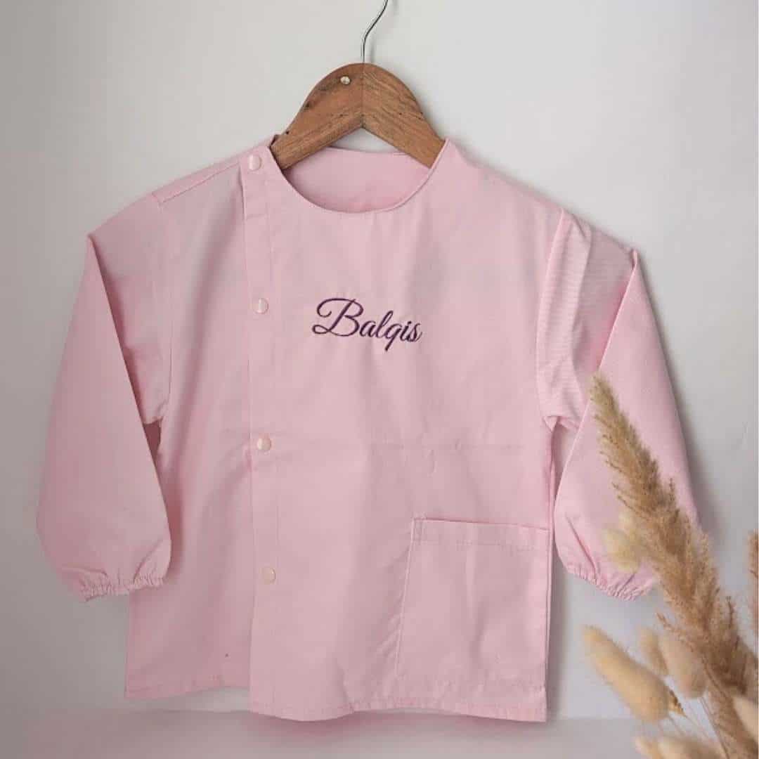 tablier ecole rose(9) Tablier en tissus pour école maternelle couleur rose modèle manches longue pour filles brodé du prénom en violet