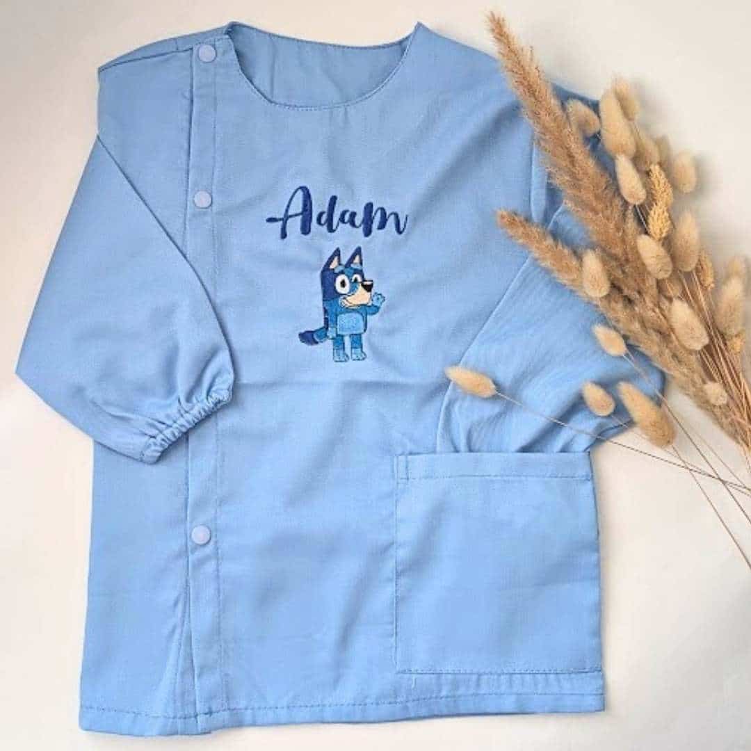 Tablier en tissus pour école maternelle couleur bleu modèle manches longue pour garçon brodé du prénom Adem en bleu