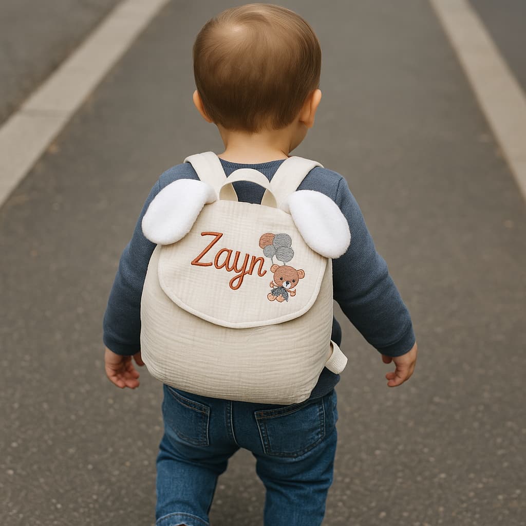 Petit garcon marchant dans la rue portant son sac à dos personnalisé d'une broderie de son prénom Zayn en marron et d'un motif de petit ourson