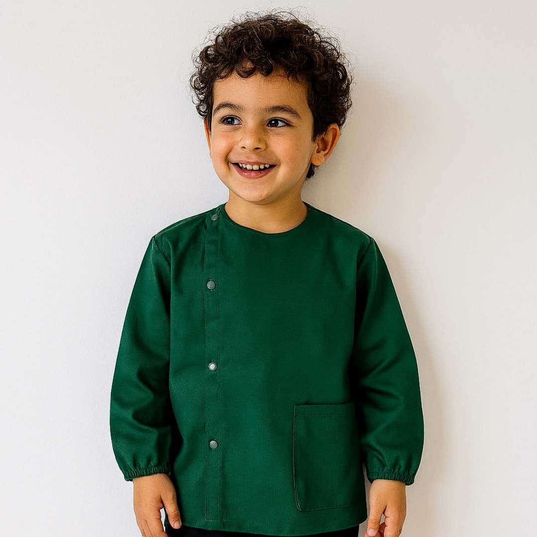 Petit garcon portant un tablier en tissus manche longue vert pour la maternelle brodé de son prénom