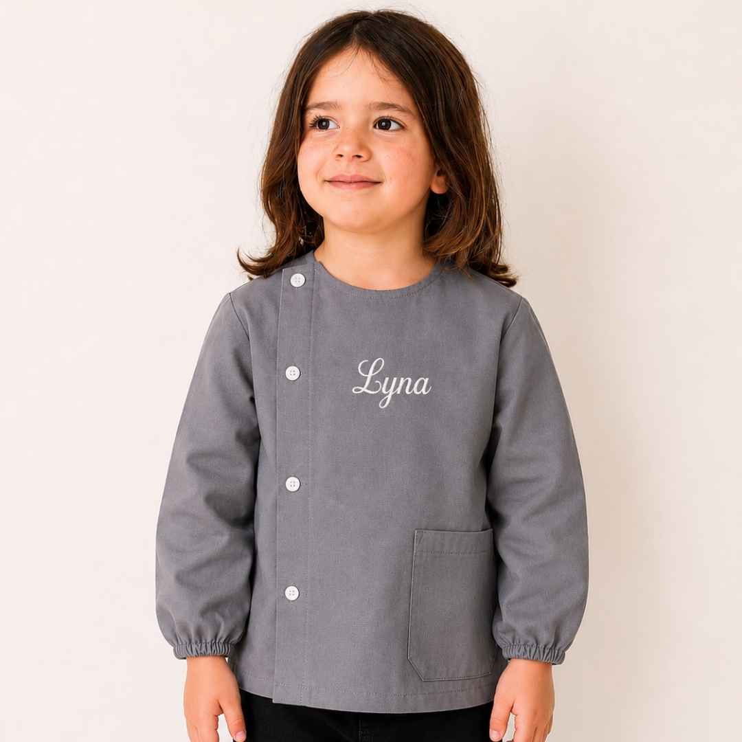tablier maternelle gris en tissus brodé du prénom Lyna en blanc